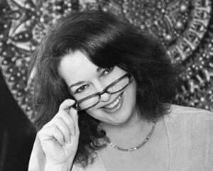 A woman holding her glasses up to the side of her face.